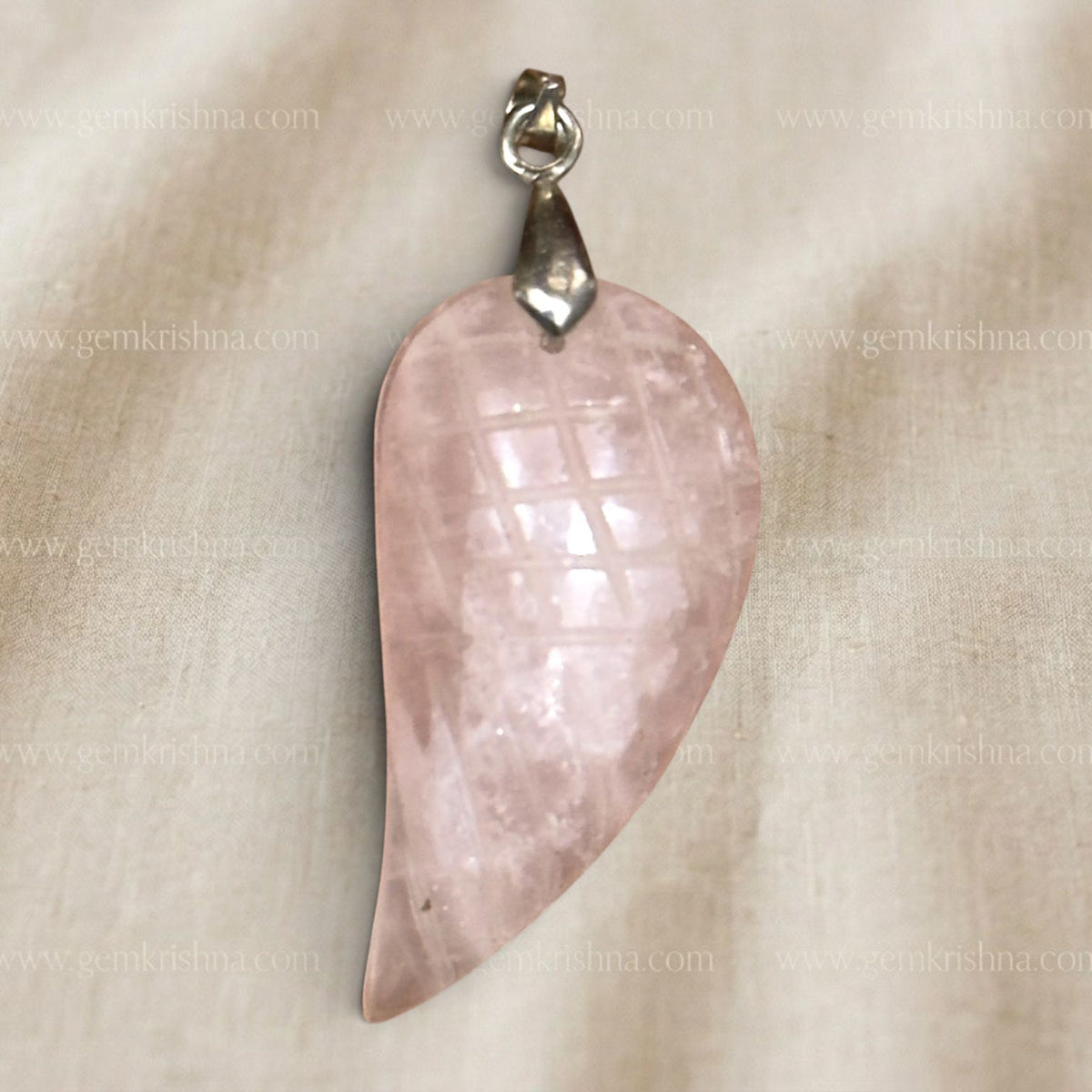 Rose quartz feather-wing locket pendant close up with silver bail on light fabric
