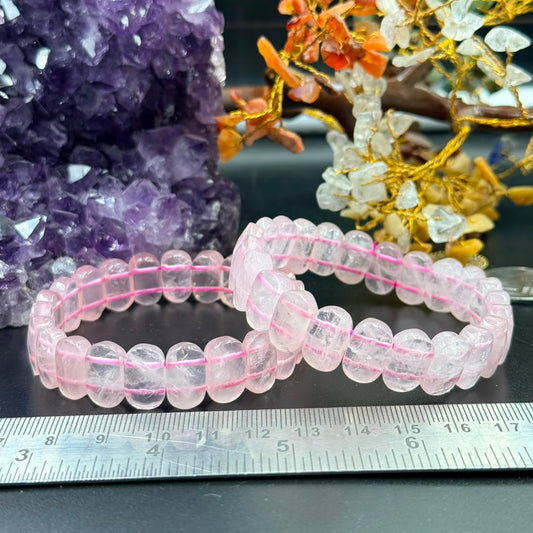 Rose quartz oval flat bead bracelet, pink strand styling on dark surface with ruler