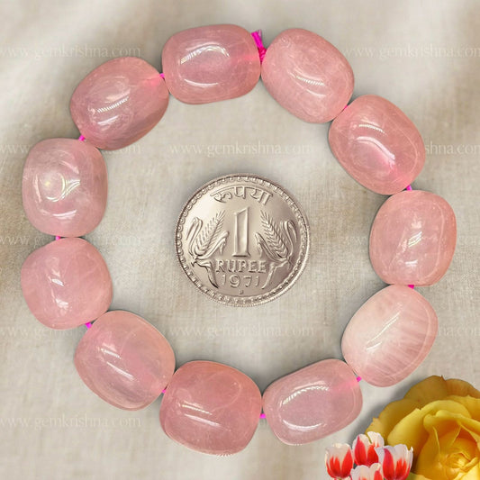 Rose quartz tumble bead bracelet close-up with pink oval stones and coin for size