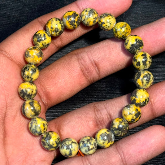 Bumblebee jasper bracelet in a hand with round beads in yellow, gold, and black patterns