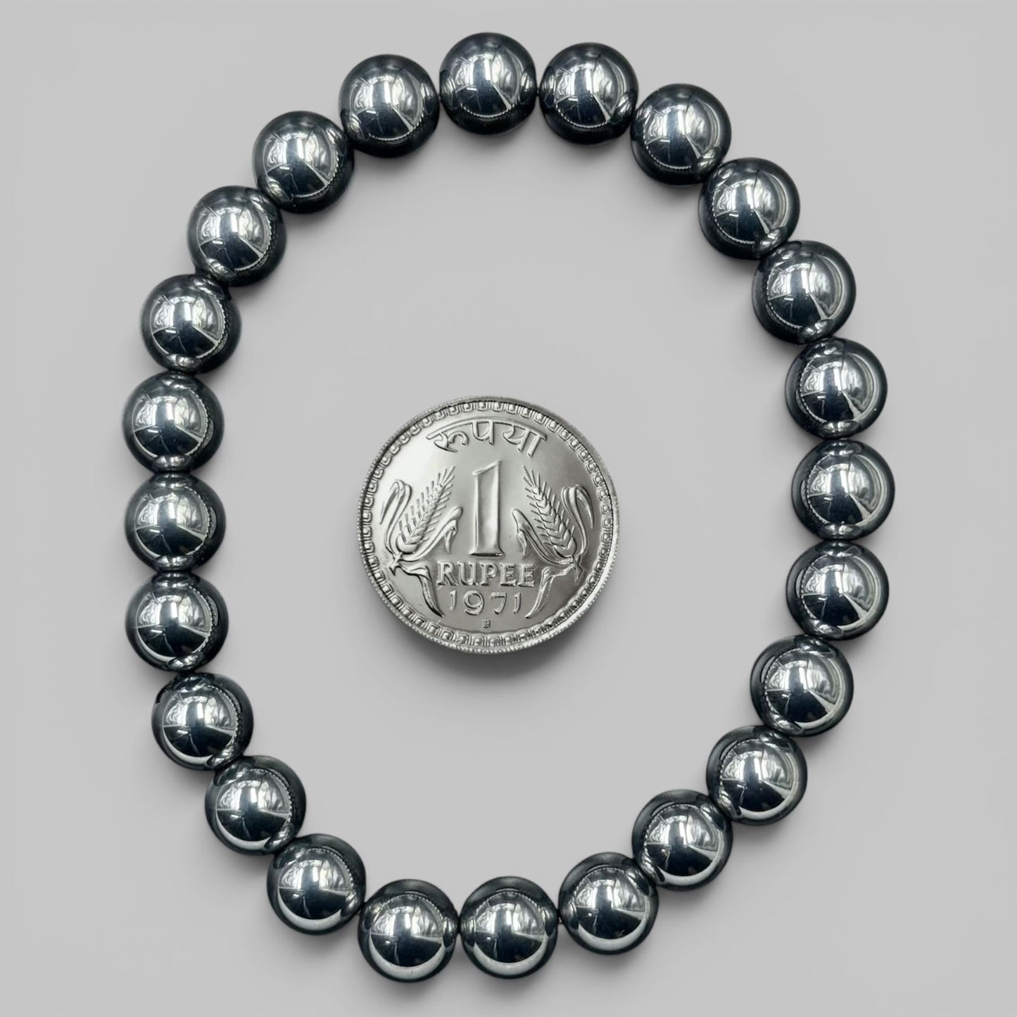 Shungite Elite bracelet view with shiny black round beads and rup ee coin for scale