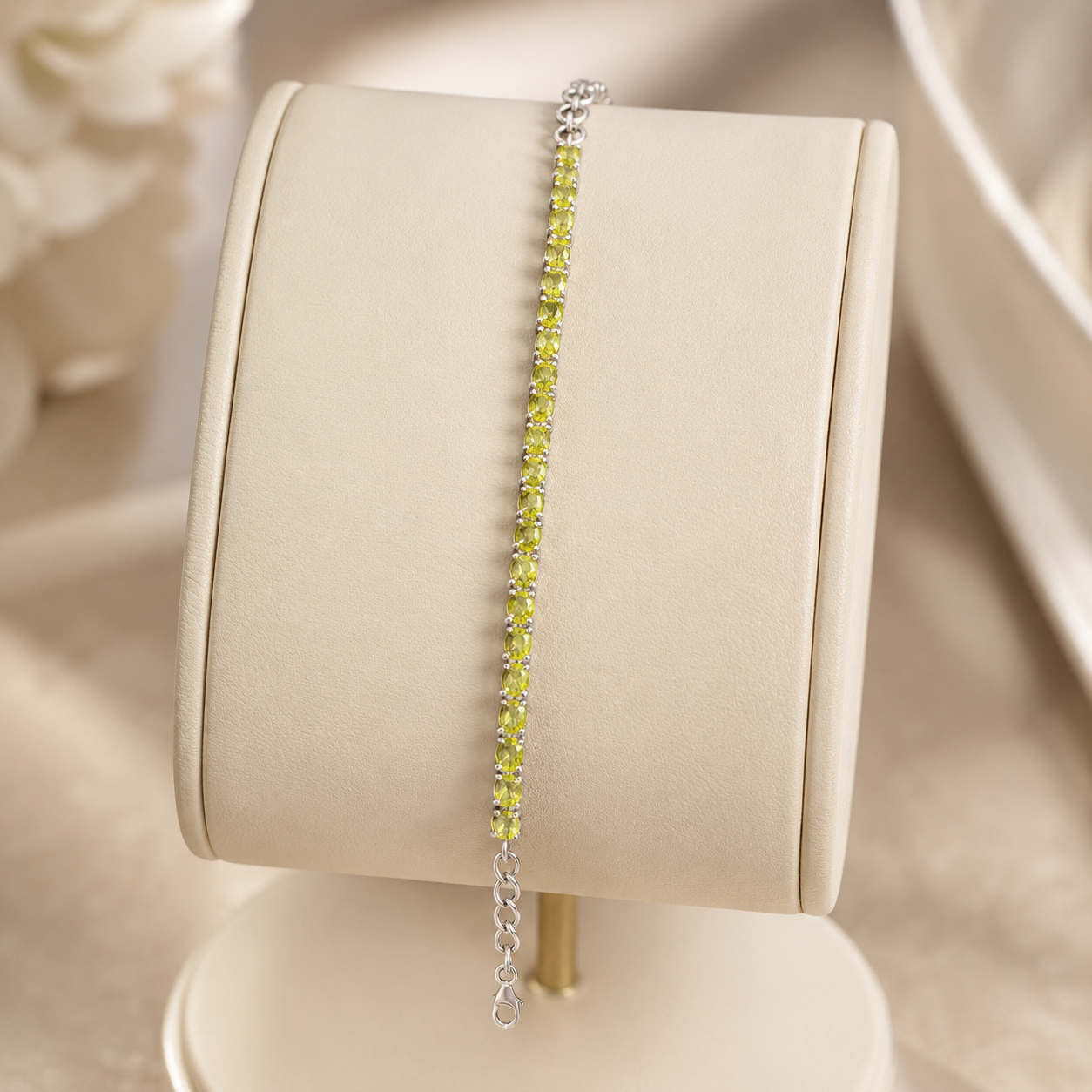 Silver green peridot tennis bracelet shown on a beige display stand with heart clasp