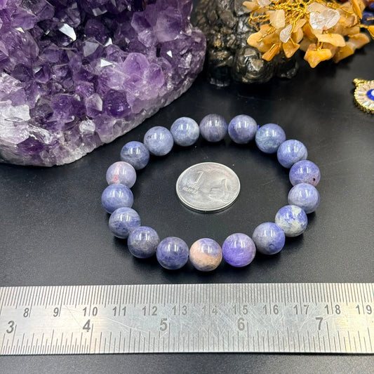 Tanzanite certified bracelet with round lavender-blue beads on a black surface and ruler