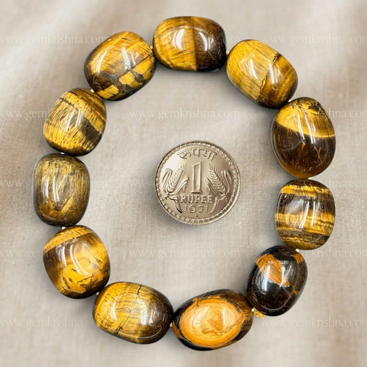 Tiger eye tumble bracelet with glossy oval beads arranged in a circle, rupee coin for size