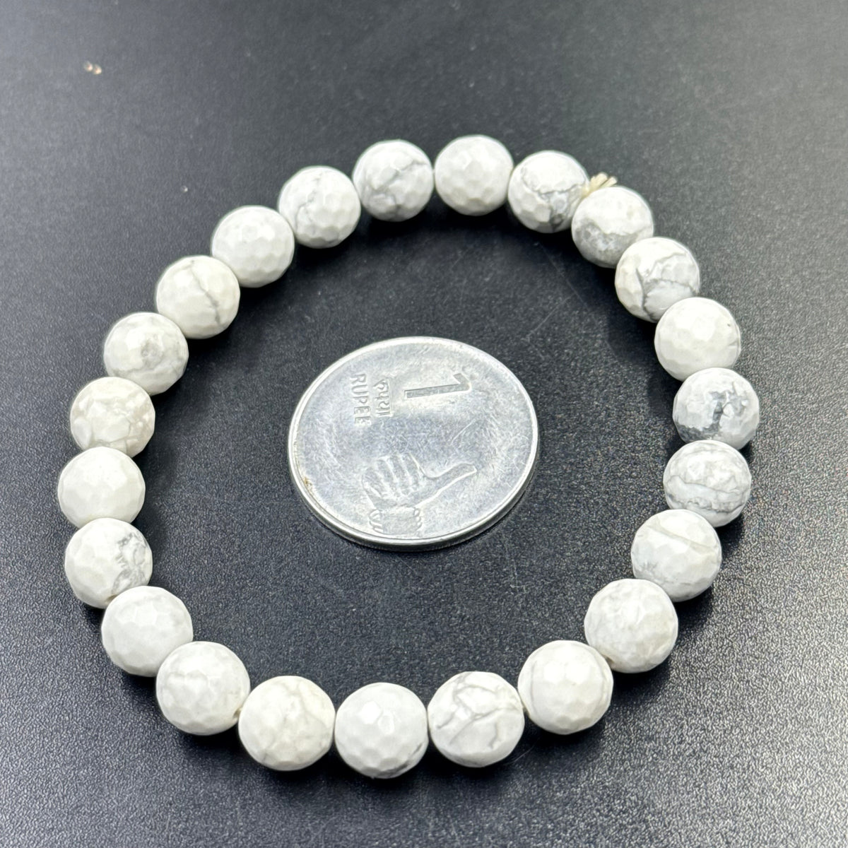 Howlite beaded bracelet close-up showing round white stones with coin for size