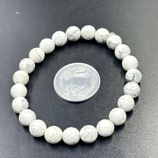 Howlite beaded bracelet close-up showing round white stones with coin for size