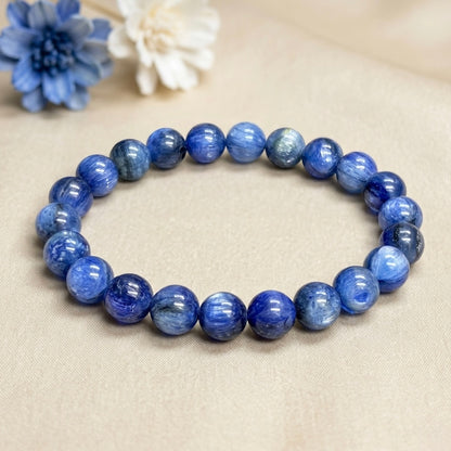 Blue Kyanite Bracelet with polished round beads arranged in a circle on beige fabric background