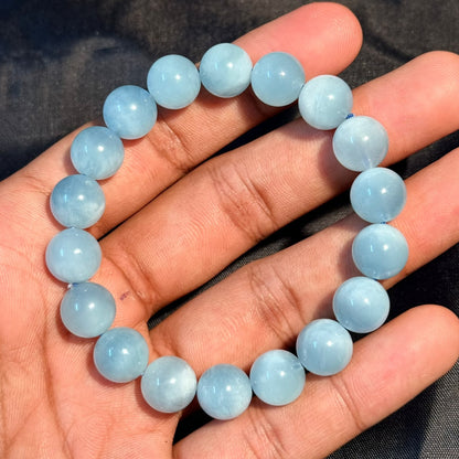 Aquamarine Bracelet with round light blue beads held in hand on black background