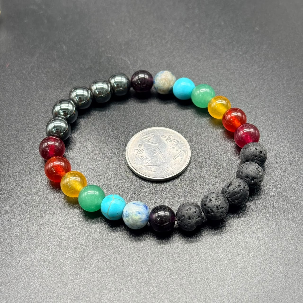 7 Chakra Balance Bracelet with colorful round beads and an Indian one rupee coin on black background
