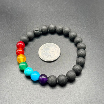 7 Chakra Balance Bracelet with seven colored beads and black textured beads, displayed next to a coin.