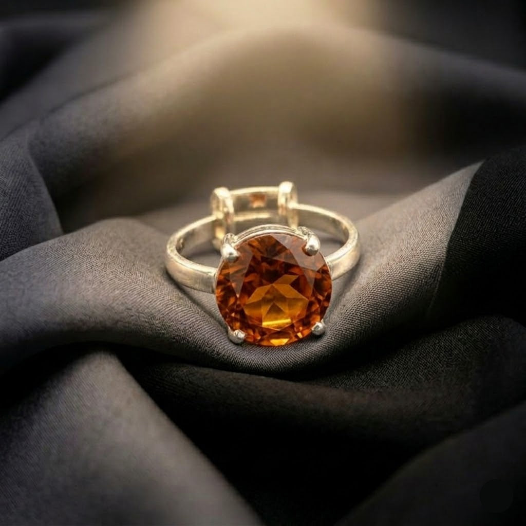 Silver ring with a large siloni gomedh/hessonite garnet gemstone on dark fabric