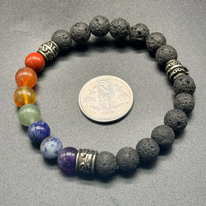 7 Chakra Balance Bracelet with seven colorful stone beads and black porous lava beads alongside currency coin