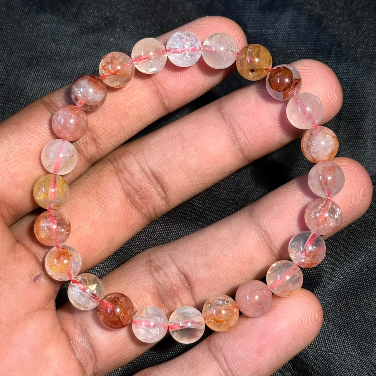 Hematoid Quartz/Lepidocrocite Bracelet with round translucent beads featuring orange and yellow inclusions held in hand