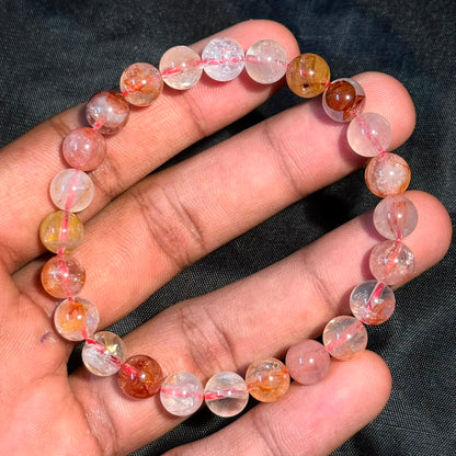 Hematoid Quartz/Lepidocrocite Bracelet with round translucent beads featuring orange and yellow inclusions held in hand