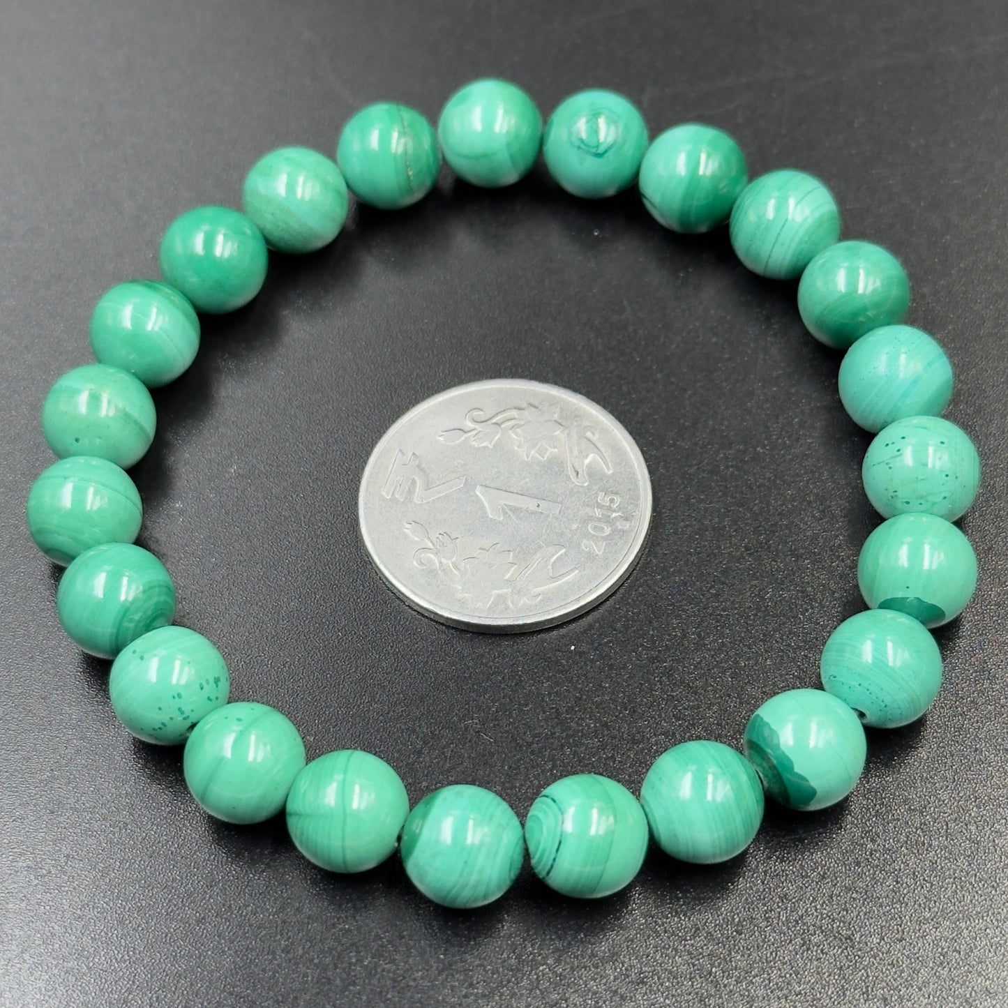 Malachite Bracelet with light green round beads and silver coin on black background