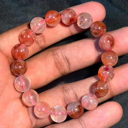 Hematoid Quartz/Lepidocrocite bracelet with round translucent beads in a hand on black background
