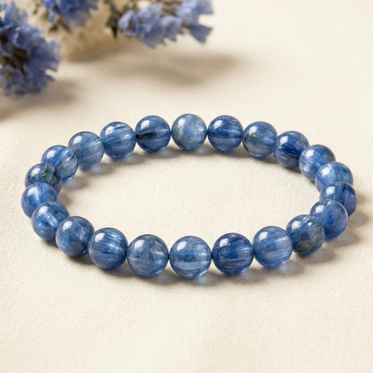 Blue Kyanite Bracelet with round polished blue beads arranged in a circular design on beige fabric background