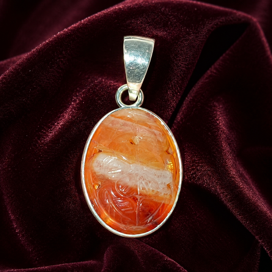 925 silver carved carnelian oval pendant with red-orange gemstone on burgundy velvet