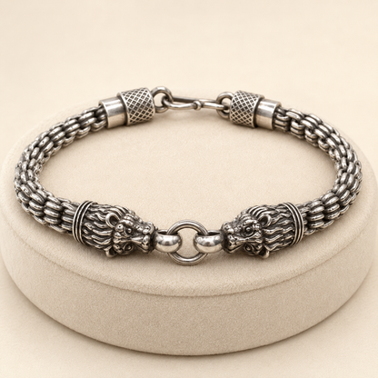 925 silver men’s double lion-head bracelet with textured barrel accents and clasp, laid on jewelry stand