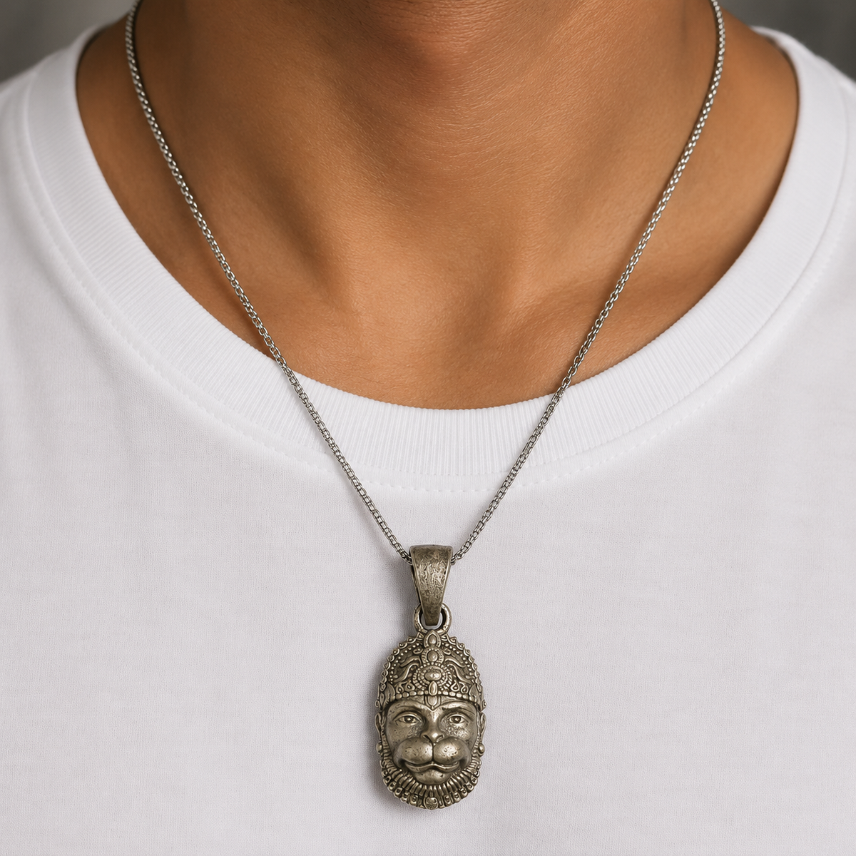 Lord Hanuman face pendant in 925 silver hanging from a fine chain on a white shirt