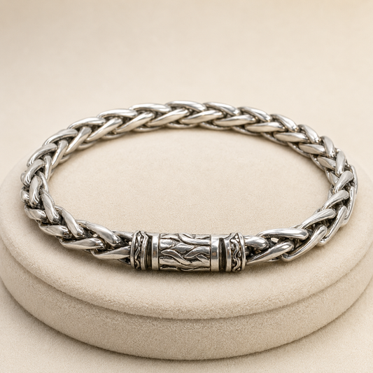 925 silver men’s braided bracelet with engraved center detail on beige jewelry cushion