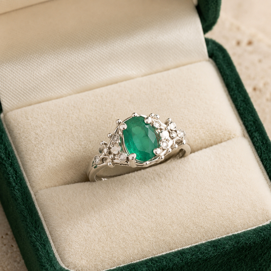 925 silver oval emerald panna ring with ornate halo setting on green velvet