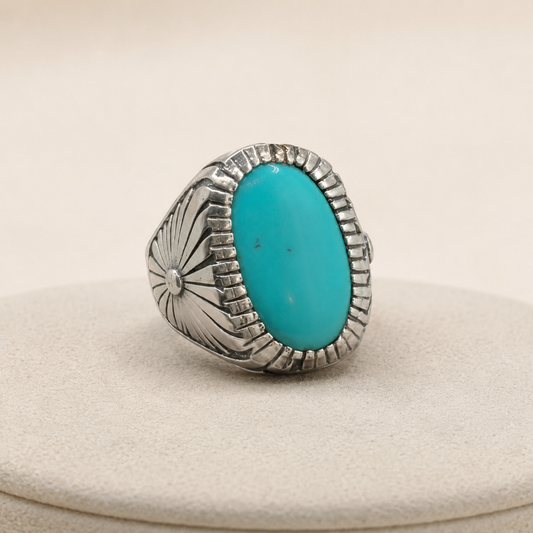 925 silver oval turquoise statement ring with carved sunburst details on a cream display