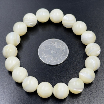 Mother of Pearl Bracelet with round beads arranged in a circle around a coin on black surface