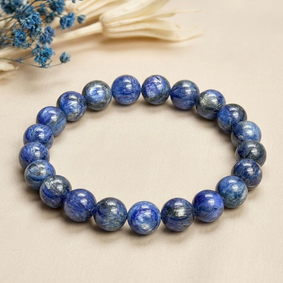 Blue Kyanite Bracelet showing round polished beads with varying blue and gray streaks on beige background