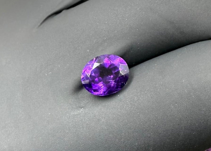 Faceted purple gemstone on a gray background