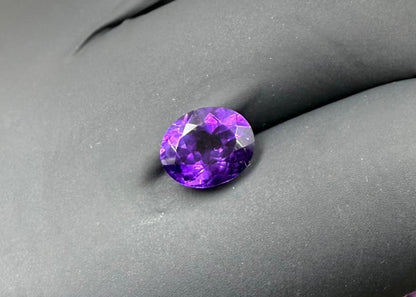 Faceted purple gemstone on a gray background