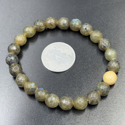 Labradorite bracelet with round beads and one cream-colored bead next to a coin.