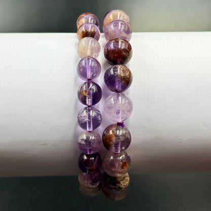 Two strands of round Ametrine Bracelet beads in varying shades of purple and amber on a white display stand