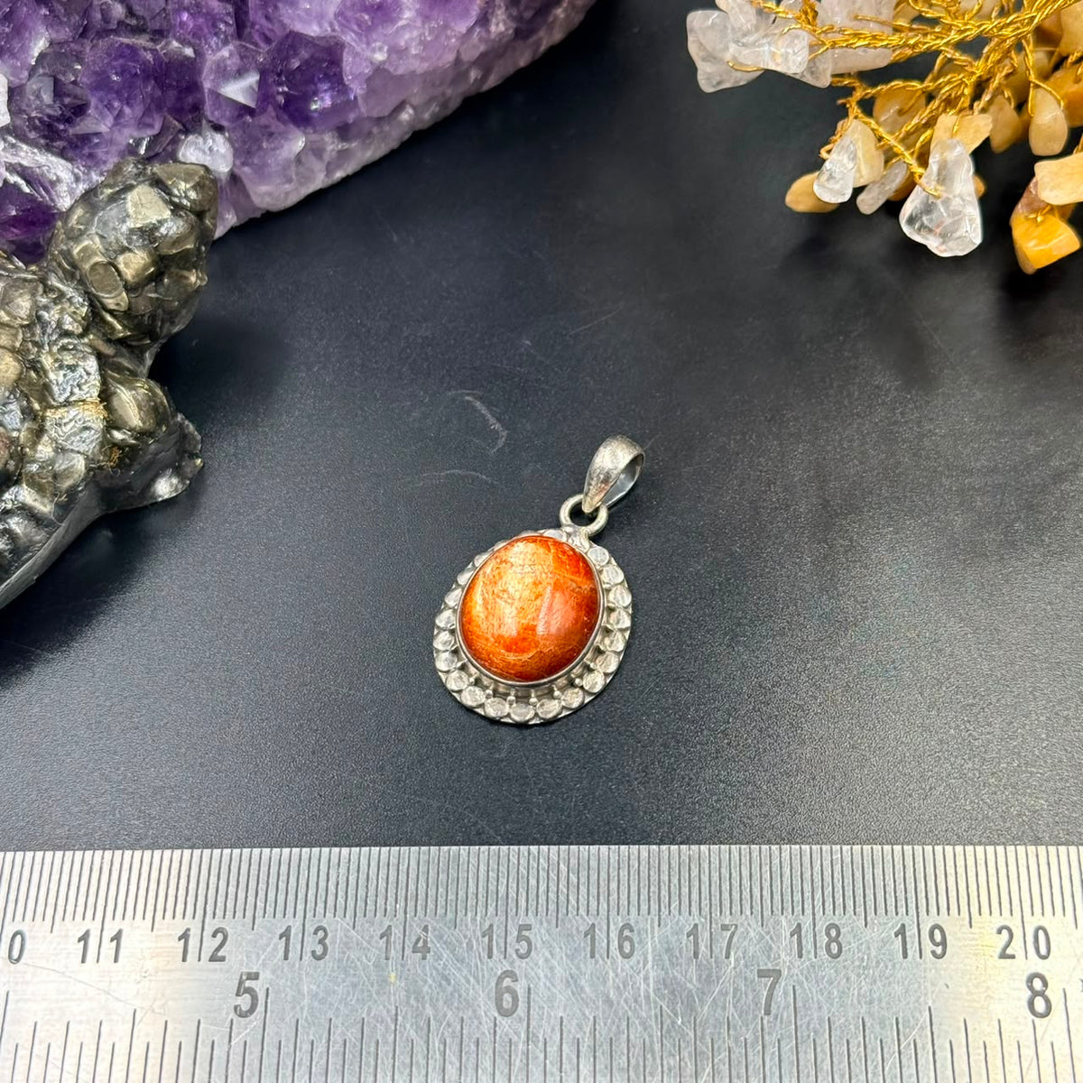 AAA sunstone silver locket pendant with orange cabochon center on black background