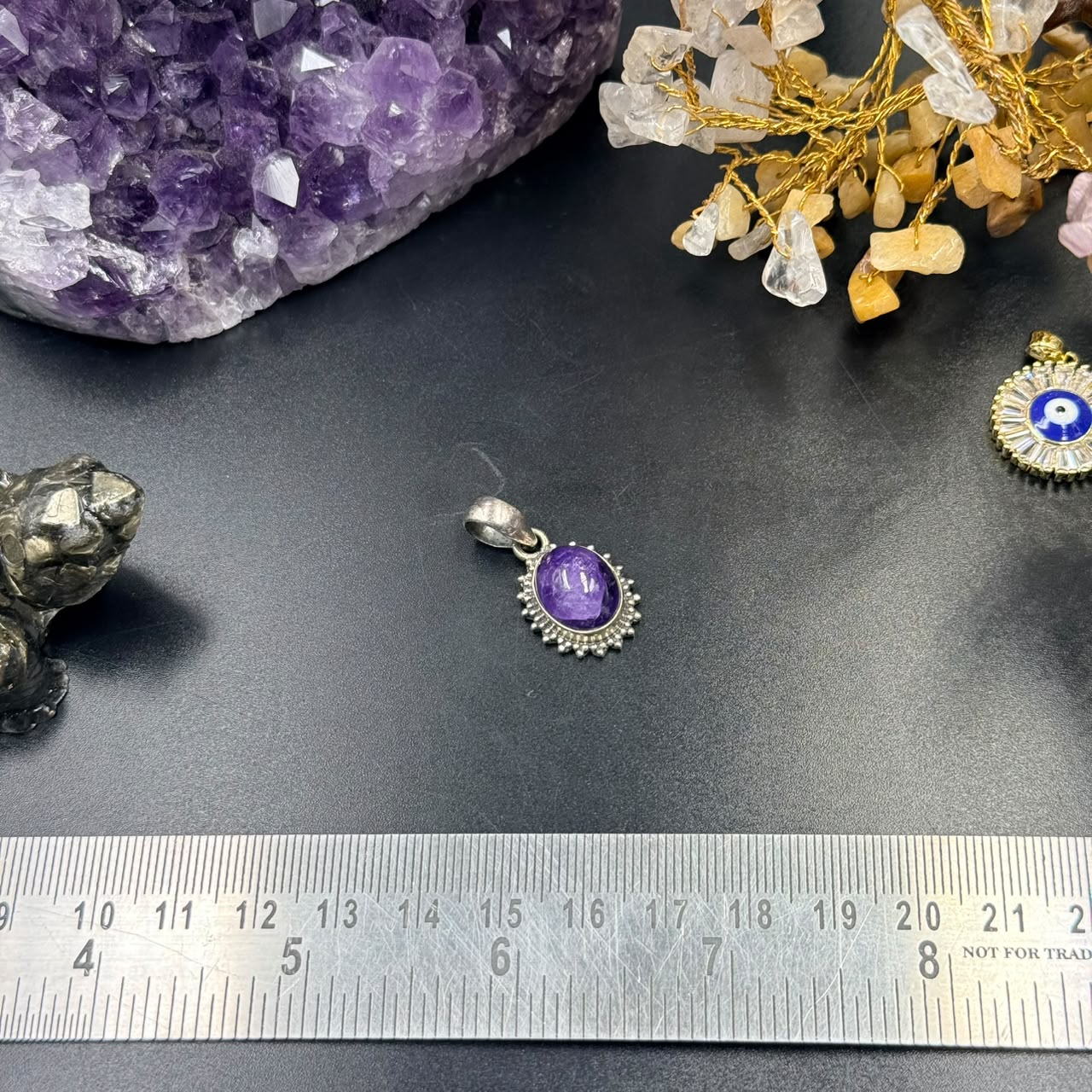 Amethyst oval locket pendant in 925 silver with decorative bezel on dark background and ruler
