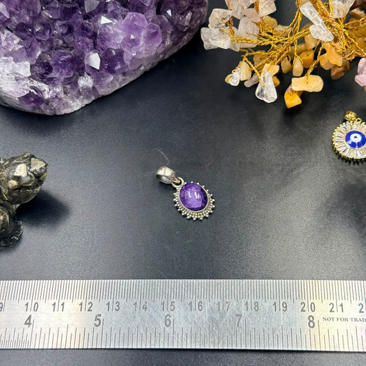 Amethyst oval locket pendant in 925 silver with decorative bezel on dark background and ruler