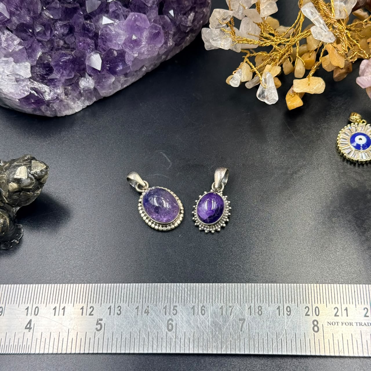 Two amethyst locket pendants in 925 silver with oval stones and decorative borders on dark background
