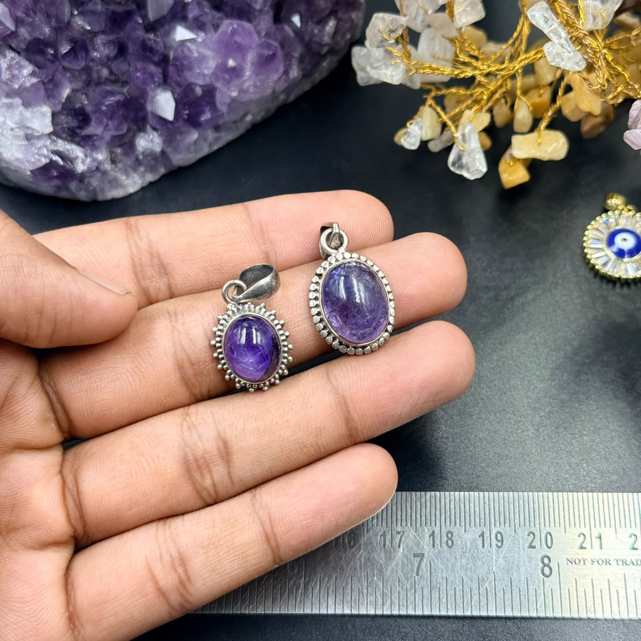 Amethyst oval locket pendant in 925 silver shown in hand for scale on dark background