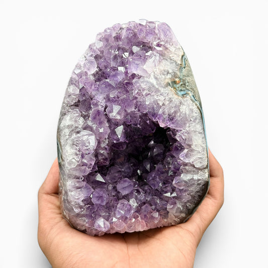 Handheld amethyst cluster raw geode cave with purple crystals and pale quartz layers
