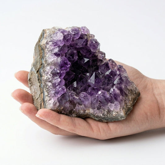 Raw amethyst geode crystal cluster held in hand for scale, natural purple rock interior