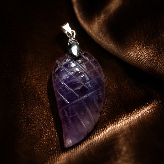 Amethyst wing feather locket pendant with silver-tone bail on dark fabric background