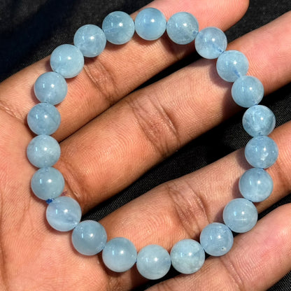Aquamarine bracelet close view on palm with round light-blue beads and glossy highlights