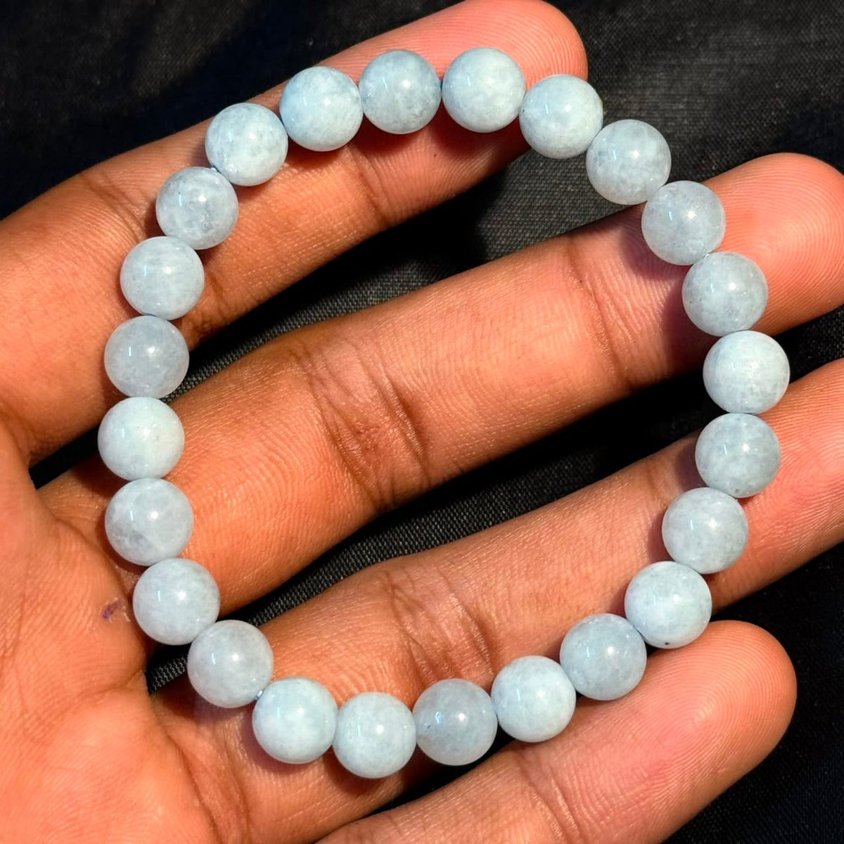 Aquamarine bracelet shown on an open palm with round light-blue beads and shine