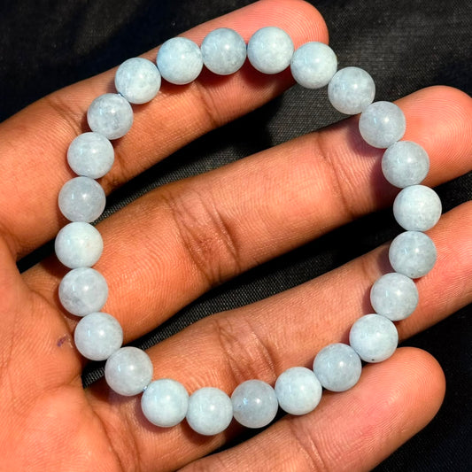 Aquamarine bracelet shown on an open palm with round light-blue beads and shine