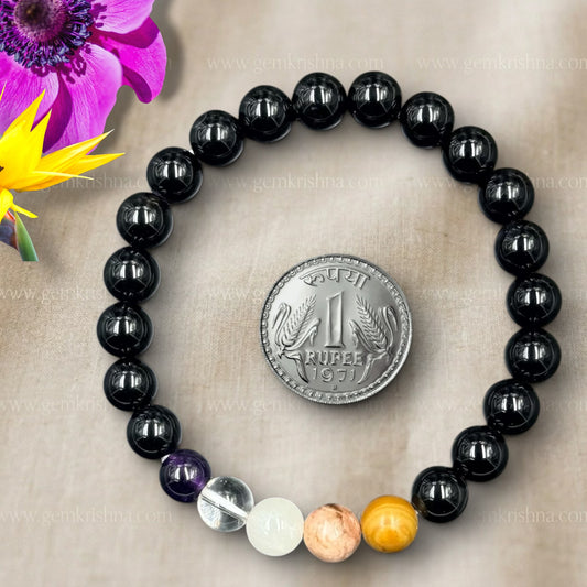 Aquarius bracelet close-up with black bead strand and gemstone accent beads beside a rupee coin
