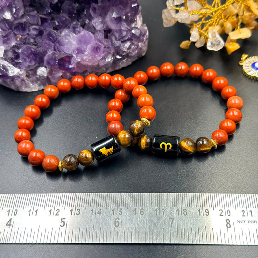 Aries (Mesh) zodiac bracelet laid out with tiger eye and red jasper beads on gray background