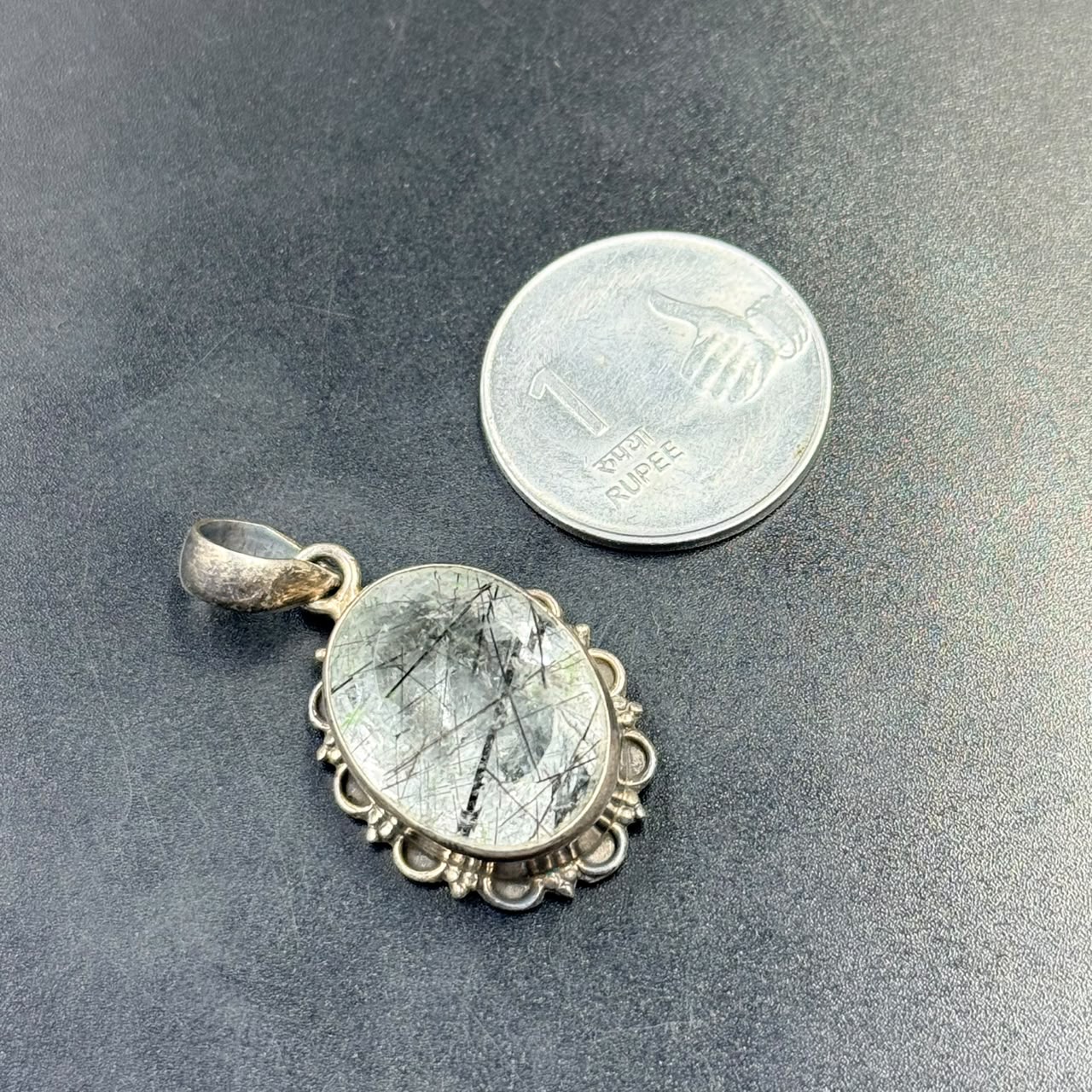 Black rutilated quartz locket pendant in 925 silver with ornate frame on dark background