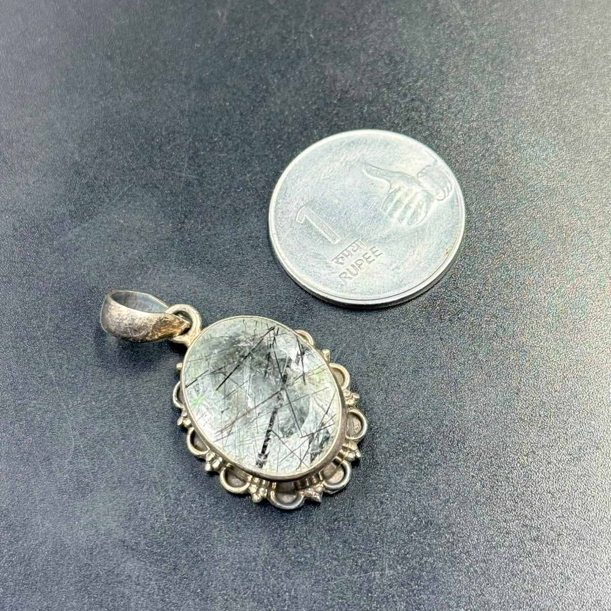 Black rutilated quartz locket pendant in 925 silver with ornate frame on dark background