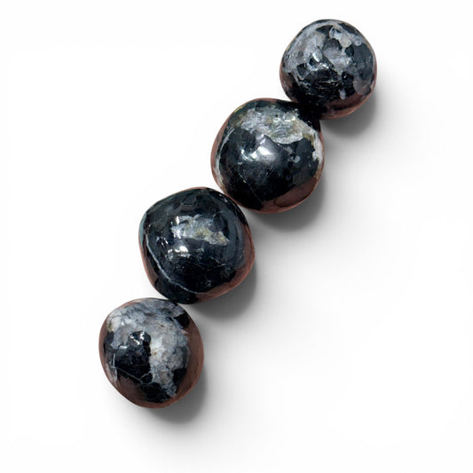 Black tourmaline free form semi polished spheres arranged on a white background