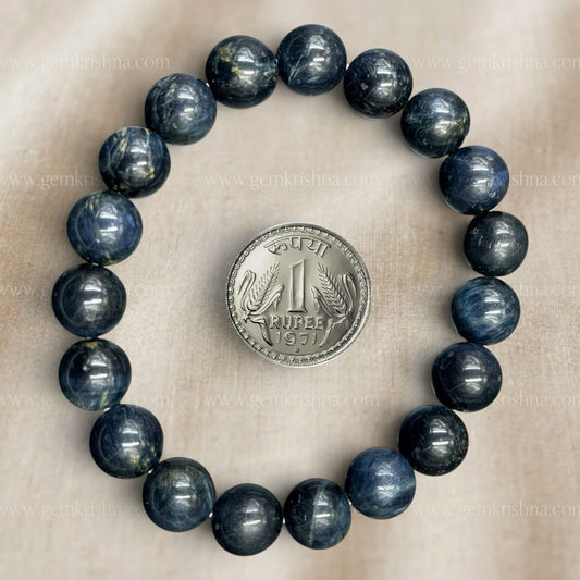 Blue tiger eye bead bracelet with a silver coin for size comparison on beige background